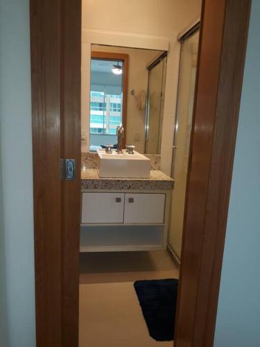 a bathroom with a sink and a mirror at Apartamento uma quadra do mar, melhor localização in Capão da Canoa