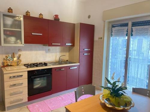 una cucina con armadi rossi e un tavolo con ananas di Casa Vacanze - Oliveri - Sicilia a Oliveri