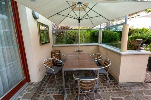 a wooden table with chairs and an umbrella on a porch at Ferienhaus Tolazzi in Arnoldstein