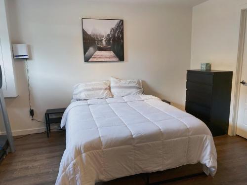 a bedroom with a white bed with a black dresser at Sous-sol dans la Ville de Québec in Quebec City