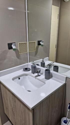 Un baño con un lavabo blanco y un espejo. en Departamento Centro Lynch II, en Temuco