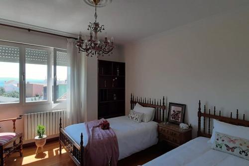 a bedroom with two beds and a chandelier at Arrochela apartamento in Ribeira