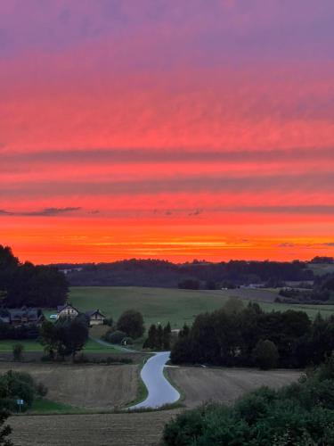 a sunset over a road in a field at Apartament Nadziei in Chmielno
