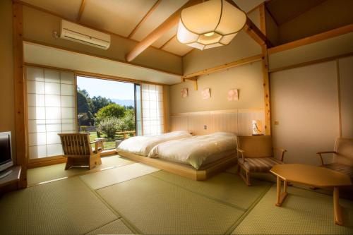 a bedroom with a bed and a large window at Tsutaya Tokinoyado Kazari in Kiso