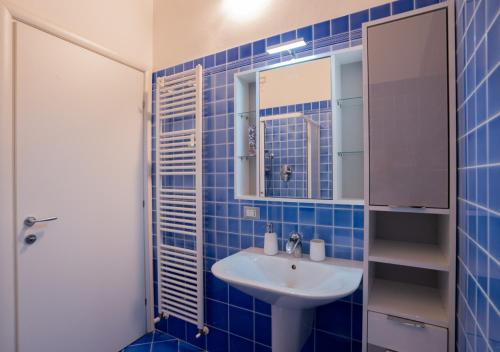 Baño de azulejos azules con lavabo y espejo en Mansarda storica Colombo in centro - parcheggio privato, en Ferrara