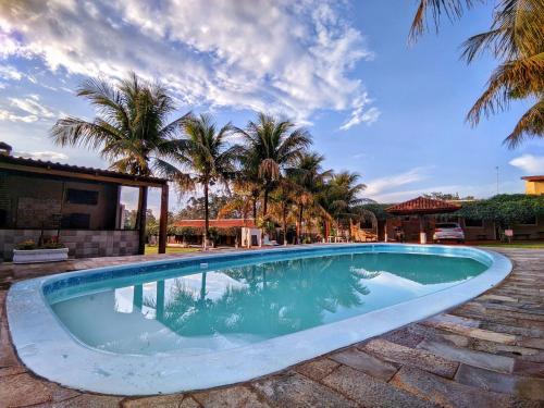a swimming pool with palm trees in the background at POUSADA POR DO SOL in Olímpia