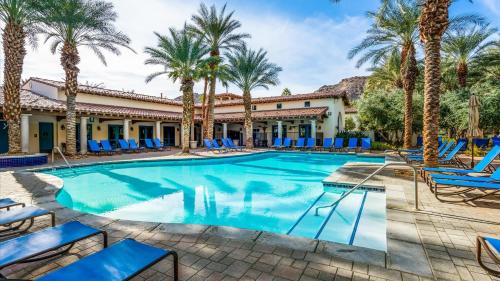 a swimming pool with blue lounge chairs and palm trees at LV030 Private Upstairs Studio w Mountain Views in La Quinta