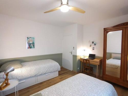 um quarto com 2 camas, uma secretária e uma ventoinha de tecto em Grand Appartement avec Jardin Bretenoux em Bretenoux