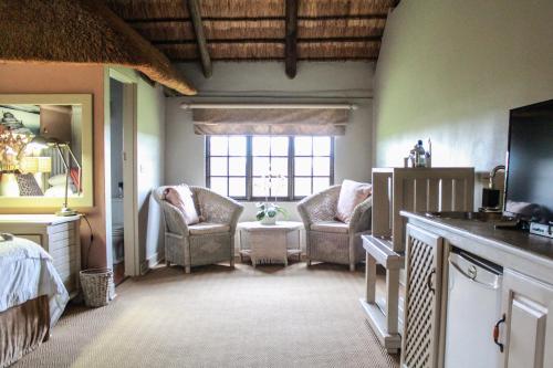 a bedroom with two chairs and a bed and a window at Siesta Guesthouse & Wedding Venue - Frankfort in Frankfort