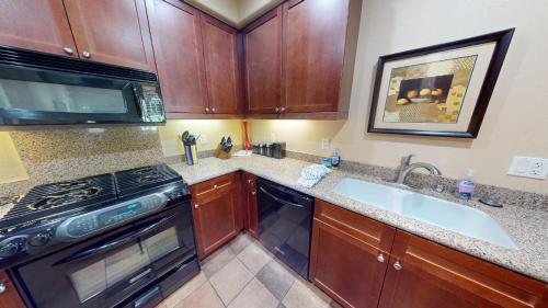 a kitchen with wooden cabinets and a stove and a sink at LV112 Delightful Upstairs 1 Bedroom Legacy Villa in La Quinta