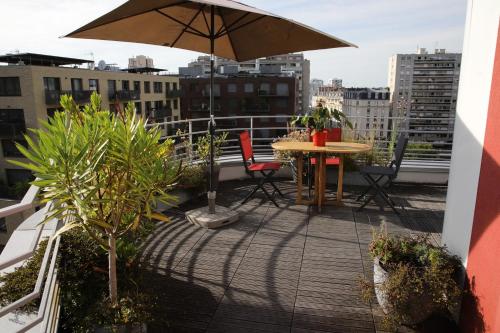 d'une terrasse avec une table et un parasol sur le balcon. dans l'établissement Duplex grande terrasse, vue sur Canal, à Paris