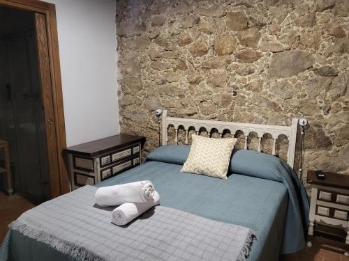 1 dormitorio con 2 camas y pared de piedra en La Casa El Cura en Madrigal de la Vera