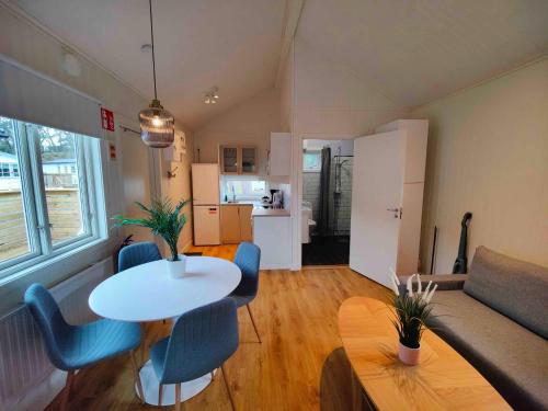 ein Wohnzimmer mit einem Tisch und Stühlen sowie eine Küche in der Unterkunft Strandbyn - Destination Råbocka in Ängelholm