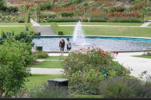 2 personnes marchant devant une fontaine dans un parc dans l'établissement Caen : Cocon moderne et chaleureux à 5mn du Centre, à Caen