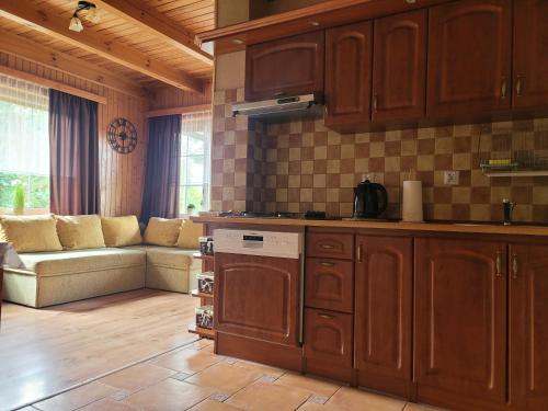 una cocina con armarios de madera y un sofá en una habitación en Kaszuby dom nad jeziorem Szczytno Duże, en Dobrzyń