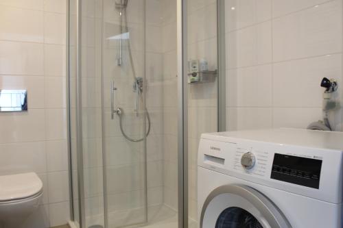 een badkamer met een douche en een wasmachine bij Duinzicht 2 in Bergen aan Zee