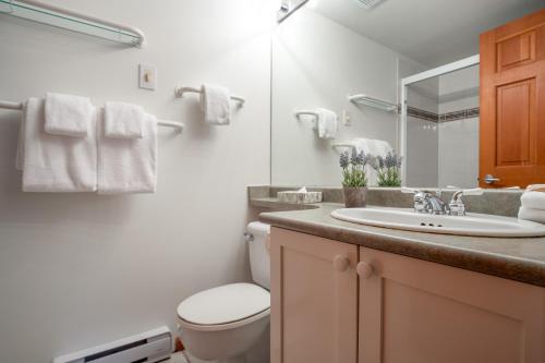 a bathroom with a sink and a toilet and a mirror at Steps From The Village with Pool and Hot Tub by Harmony Whistler in Whistler