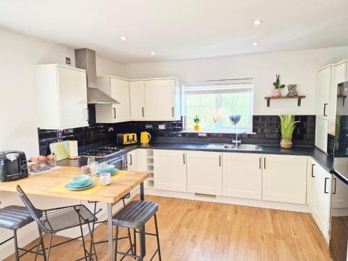 a kitchen with white cabinets and a wooden table at Spacious Luxury Serviced Apartment Stevenage Free Private Parking & WIFI by Stay Local Home Welcome Contractors Business Travellers Families in Stevenage