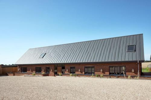 a large brick barn with a metal roof at A true British country escape! in Bucknell