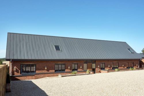 a red brick barn with a gray roof at A true British country escape! in Bucknell