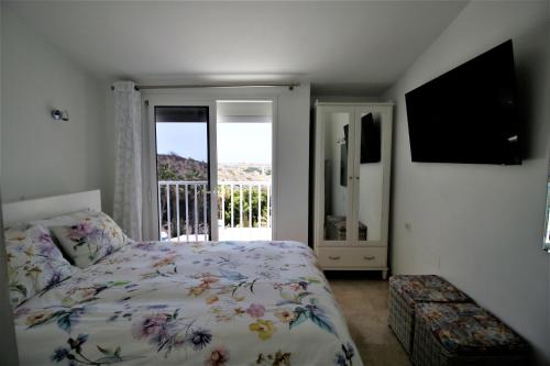 a bedroom with a bed and a balcony with a television at Sonnenland Meloneras & Maspalomas in Maspalomas