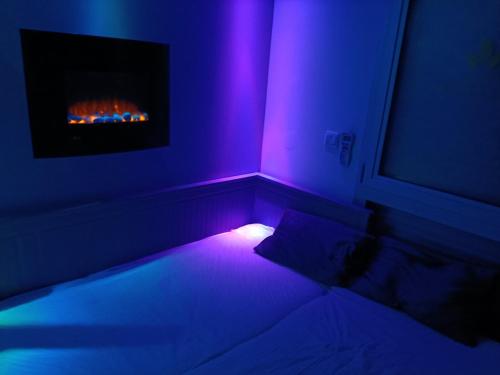 Pokój z łóżkiem i kominkiem z fioletowymi światłami w obiekcie Studette avec SPA & Jacuzzi w mieście Sète