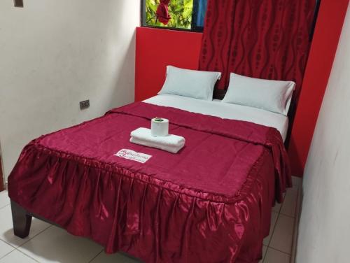 una cama roja con una toalla encima en Alojamiento Los Jardines, en Lamas