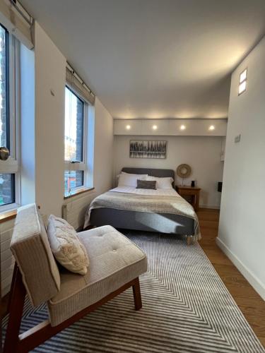 a bedroom with a bed and a chair and windows at Heart of Covent Garden central apartment - 2 bed in London