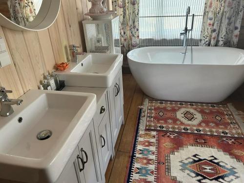 ein Badezimmer mit zwei Waschbecken, einer Badewanne und einem Spiegel in der Unterkunft Sodyba ramiam poilsiui in Kaltanėnai