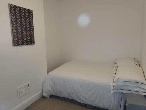 Una cama blanca en un dormitorio blanco con una foto en la pared en Affordable rooms in Gillingham en Gillingham