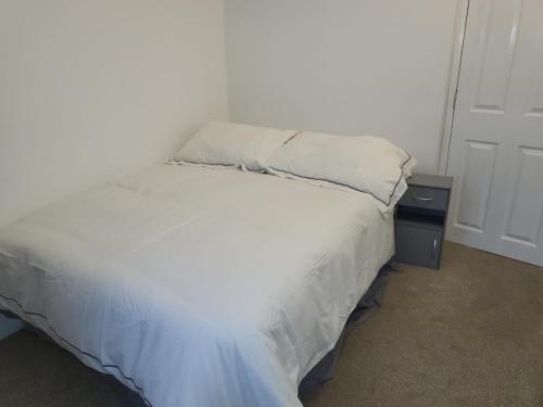 a bedroom with a white bed with a night stand at Affordable rooms in Gillingham in Gillingham