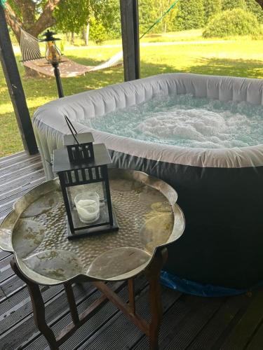 a candle on a table next to a hot tub at Sodyba ramiam poilsiui in Kaltanėnai