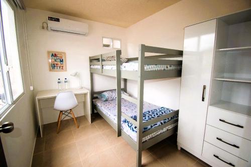 a bedroom with two bunk beds and a desk at Acogedor departamento en La Aurora 