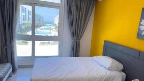 a bedroom with a bed and a large window at Direct Sea & Pool View FANADIR BAY in Hurghada