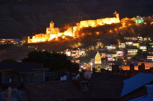 a city at night with a castle in the background at Eleon Boutique Hotel in Tbilisi City