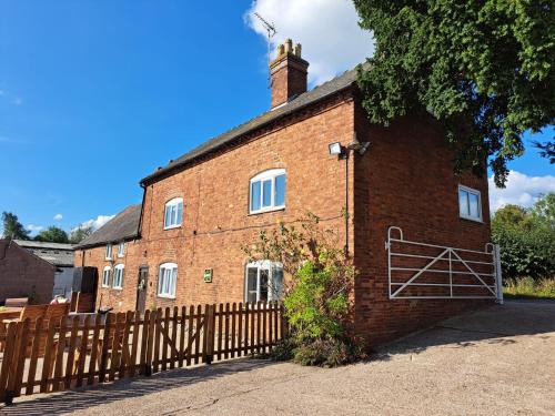 a red brick house with a wooden fence at Deepmoor Farmhouse, Doveridge, Derbys. in Doveridge