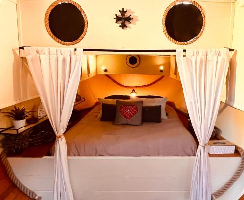 1 dormitorio con cama con dosel y cortinas en Très jolie péniche à louer, en Hédé