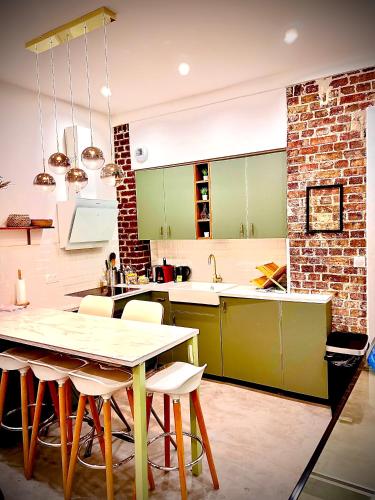kuchnia ze stołem i zielonymi szafkami w obiekcie Appartement élégant - 2 chambres - 2 salles de bain w Paryżu