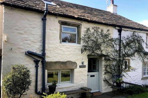 a white house with two windows and a door at Westside Cottage, Newby Yorkshire Dales National Park 3 Peaks and Near the Lake Disrict, Pet Friendly in Newby