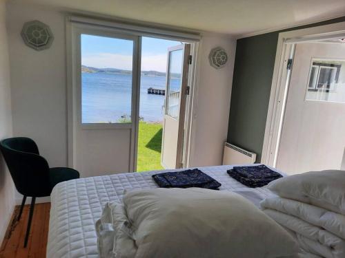 a bedroom with a bed with a view of the ocean at Cabin at the sea. public beach close with jumpingtower. in Höviksnäs