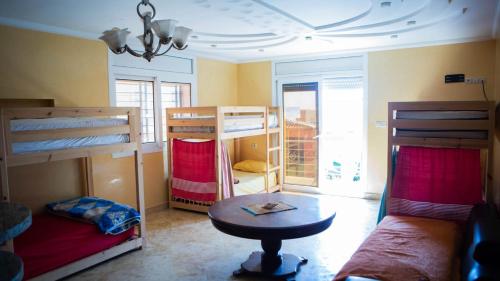 a room with bunk beds and a table and a couch at Mubaradise Surf Hostel in Imsouane