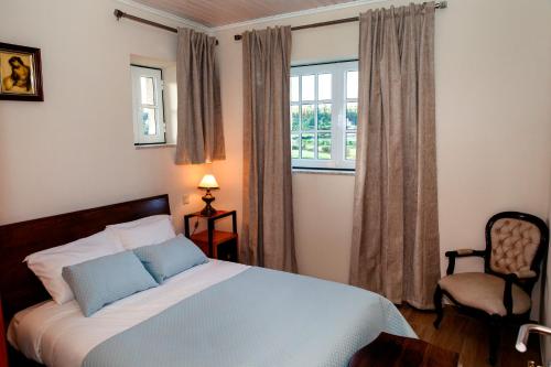 a bedroom with a bed and a chair and a window at Casinha do Sabugueiro in Ponte de Lima