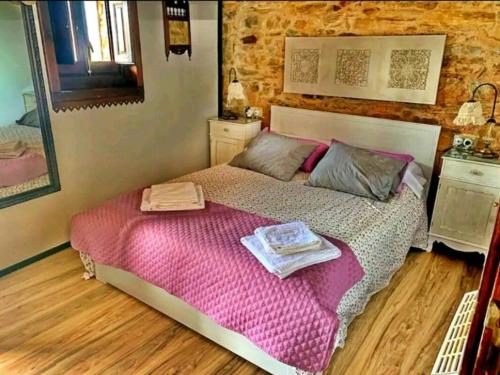 um quarto com uma cama com lençóis cor-de-rosa e um espelho em Casa do Duende em Tejedo