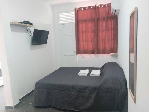 a bedroom with a black bed with two towels on it at Perle proche gare maritime et croisières in Pointe-à-Pitre