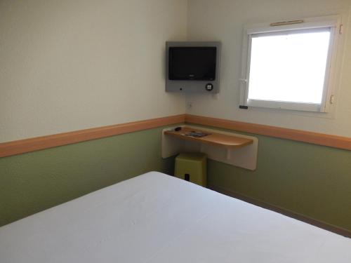 a bedroom with a bed and a tv on the wall at ibis Budget Pau Est in Pau