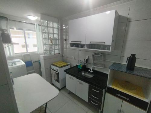 eine kleine Küche mit einer Spüle und einem Herd in der Unterkunft Apartamento em Praia Grande - Frente ao Mar in Praia Grande