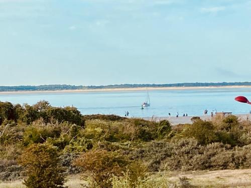people on a beach with a boat in the water at Le Gîte du Phare vue sur mer in Cayeux-sur-Mer
