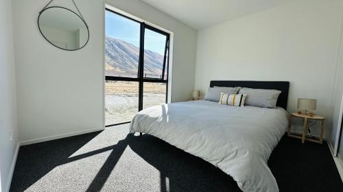 a bedroom with a bed and a large window at Manuka Vista in Twizel