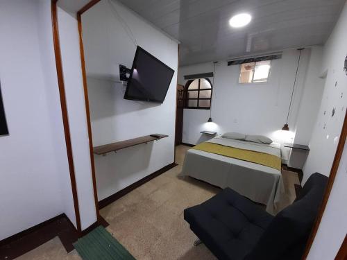 een kleine slaapkamer met een bed en een televisie bij GRAN APARTAESTUDIO EN BOSTON - MEDELLIN in Medellín