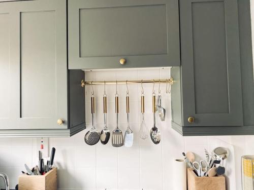 a kitchen with green cabinets and utensils on the wall at The Town House in Aylsham